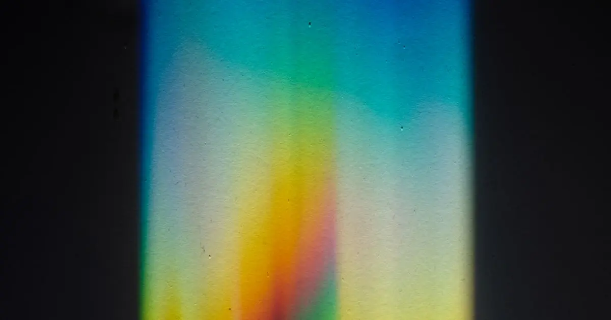 Rainbow prism light spectrum spread across a dark surface