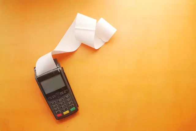 Payment terminal with printed receipt rolling out on orange background
