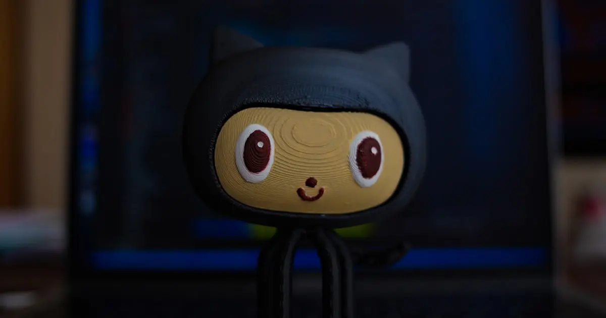 Tux penguin figurine in front of a laptop showing a code editor and terminal